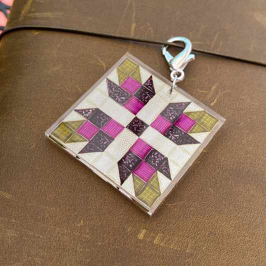 Close up of journal charm with purple flower quilt block design against leather background