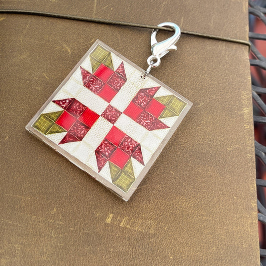 Close up of journal charm with red flower quilt block design against leather background
