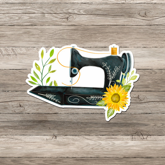 Antique sewing machine with fall sunflower sticker on gray wood background.