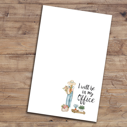 Blonde gardener with the words "I will be in my office" notepad on wood background