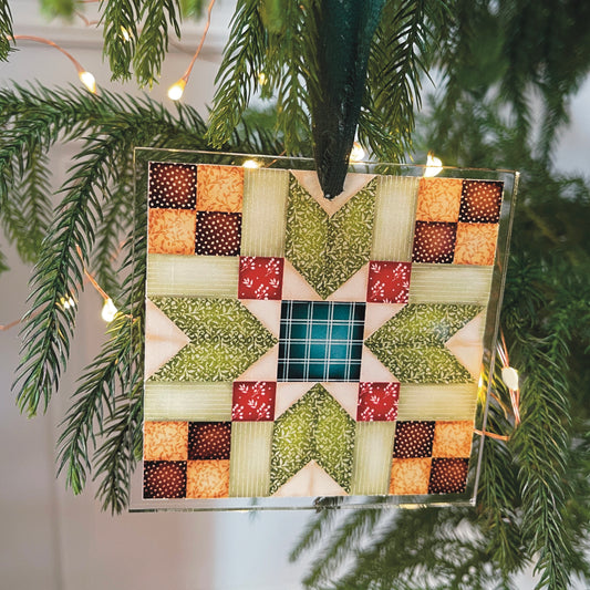 Red, green and brown Quilt block star ornament on tree with lights