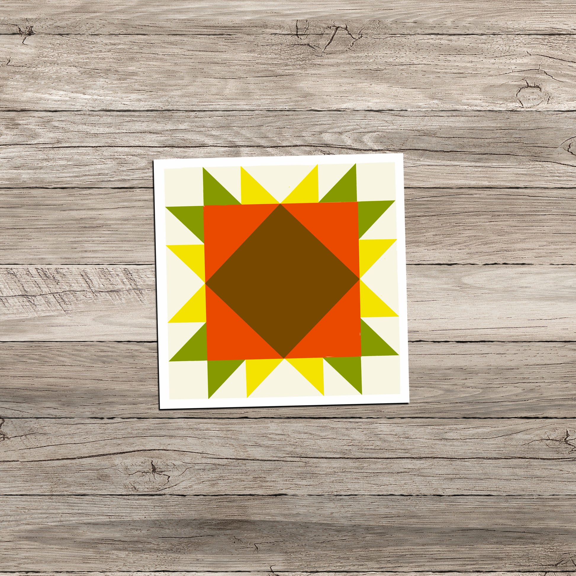 Sunflower Barn Quilt square sticker in orange, yellow, and green on a weathered light gray wood background.