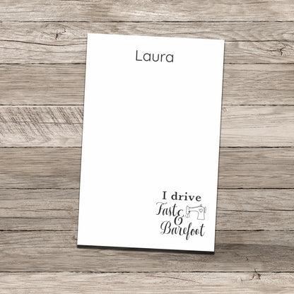 Personalized notepad featuring the name 'Laura' at the top and a sewing-themed phrase at the bottom that reads 'I drive Fast & Barefoot' with a sewing machine illustration, printed on a white background with a wood-textured backdrop.