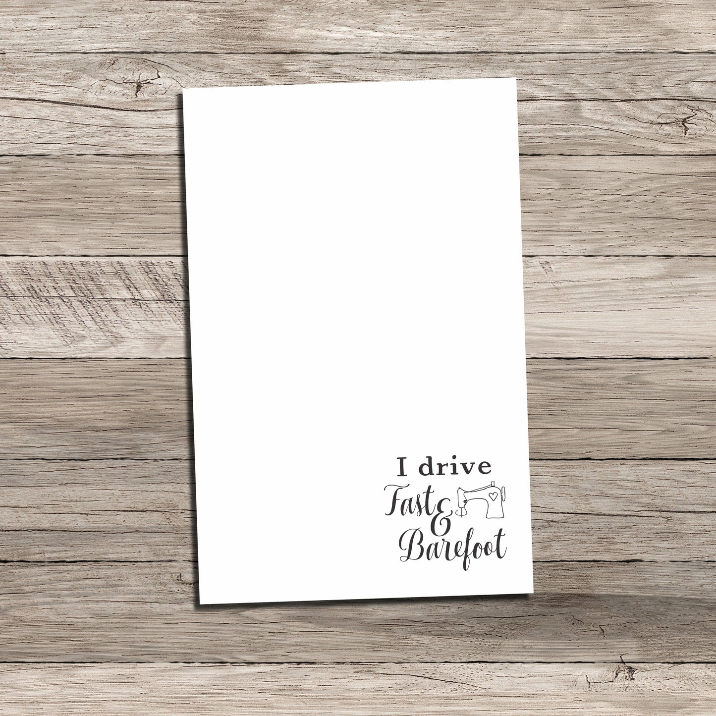 Personalized notepad featuring a sewing-themed phrase at the bottom that reads 'I drive Fast & Barefoot' with a sewing machine illustration, printed on a white background with a wood-textured backdrop.