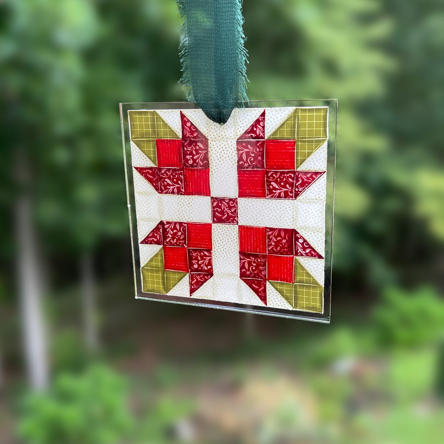 Quilt block ornament with red flower against blurred backgound