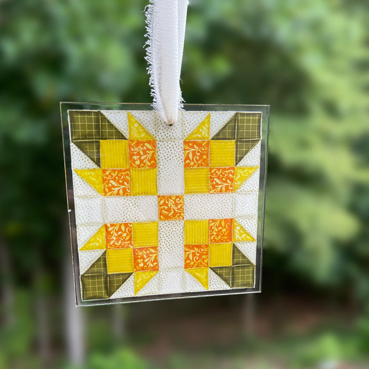 Quilt block ornament with yellow flower on blurred background