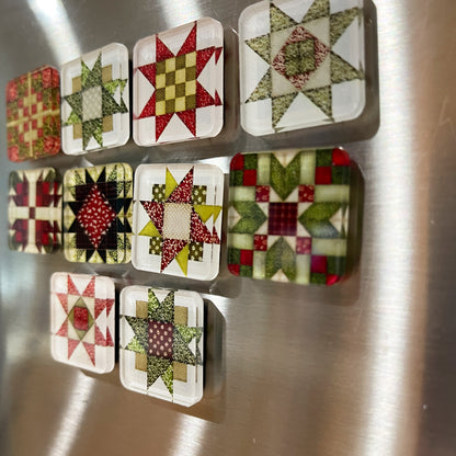 Side view of set of ten square magnets featuring colorful Christmas-themed quilt block designs in traditional red, green, and white patterns. Each magnet showcases a unique quilt patchwork design, arranged in a neat grid on a metallic background.