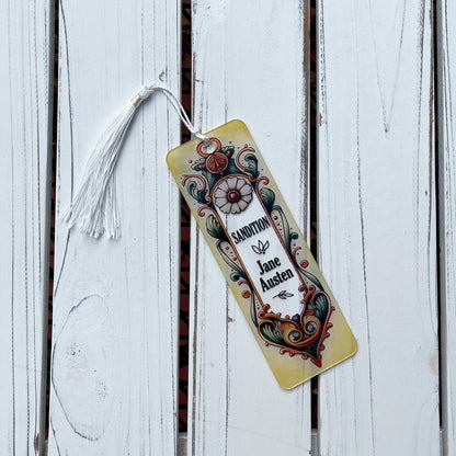 Jane Austen Sandition floral acrylic bookmark with tassel laying on rustic white wood background.